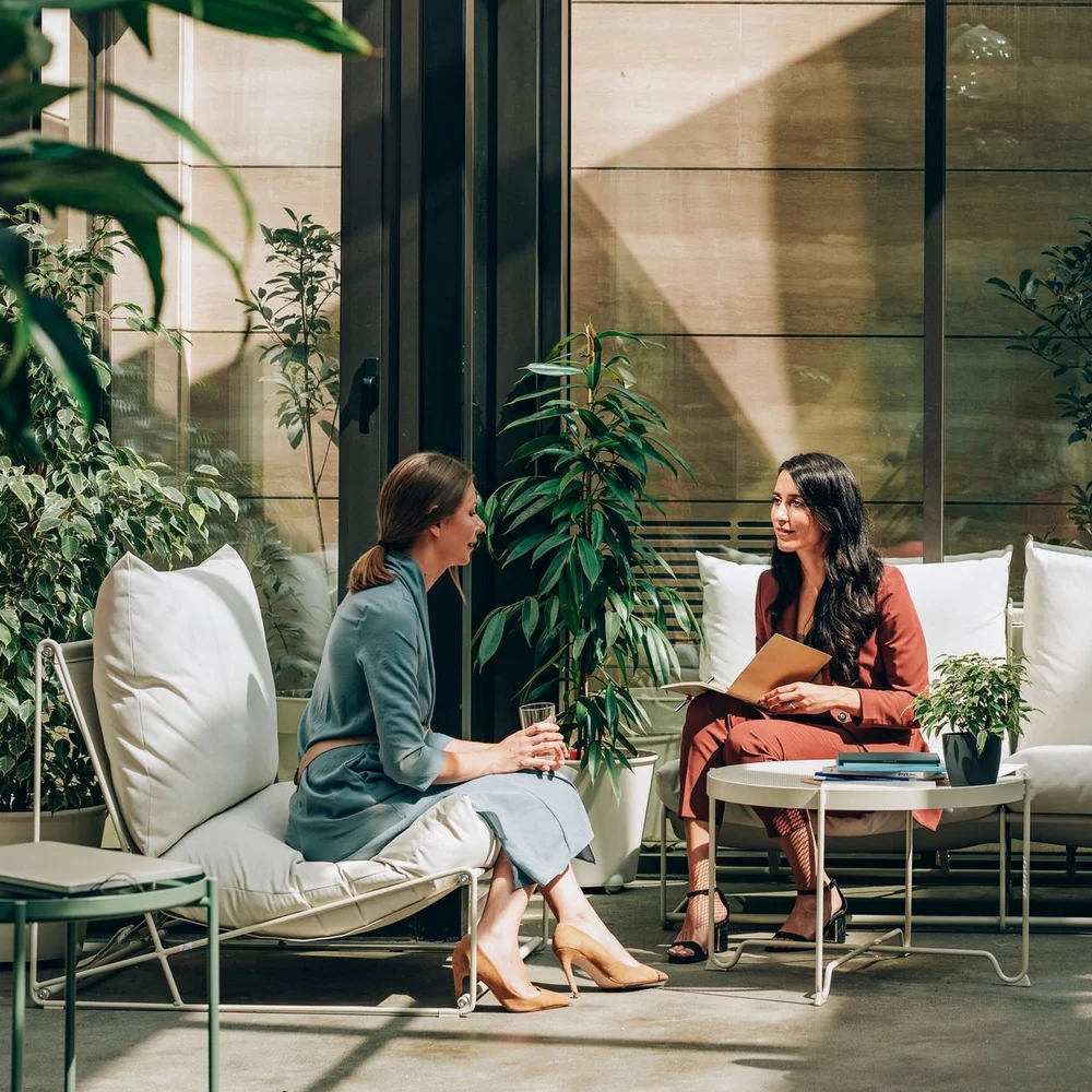 Two women in conversation during a consultation, surrounded by plants