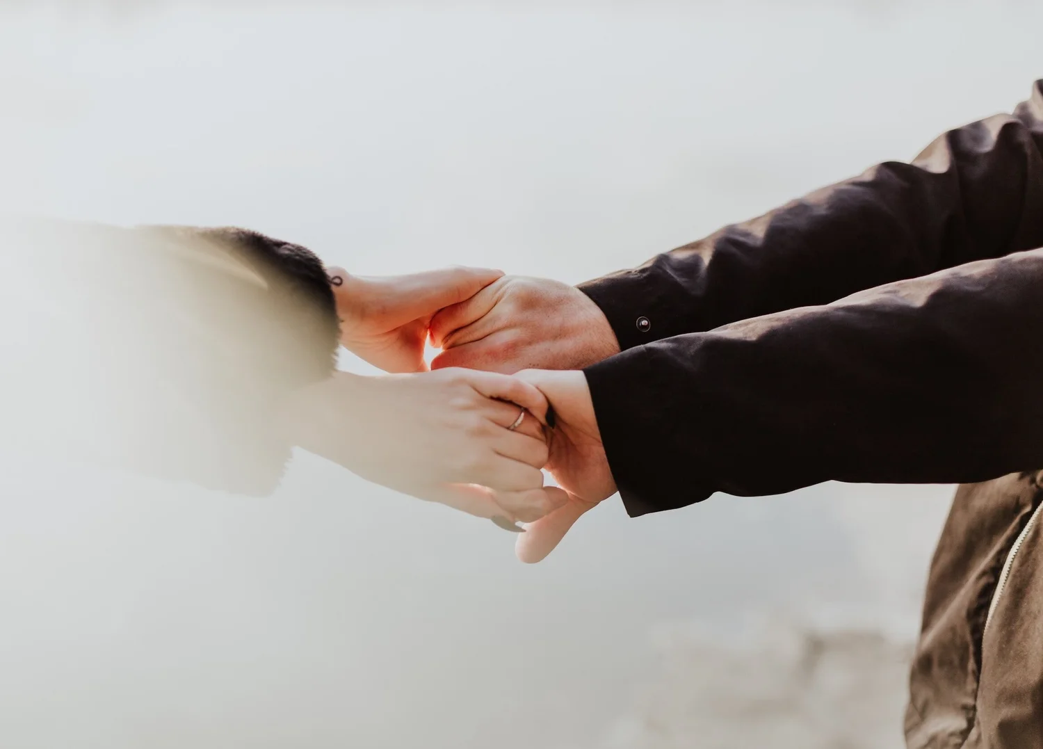 Close-up of a couple holding hands in soft outdoor light